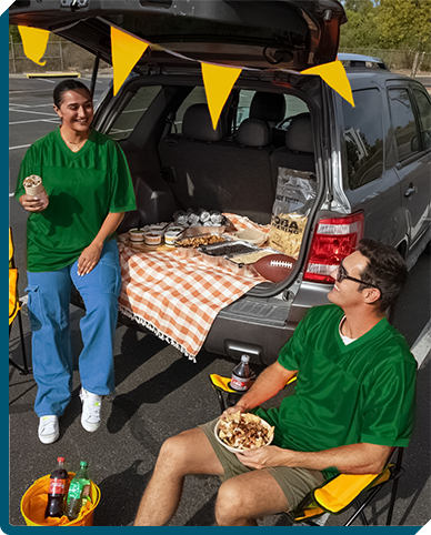 QDOBA tailgate party in full swing in a stadium parking lot, with fans in football jerseys enjoying fresh, flavorful QDOBA catering options, celebrating game day with style and delicious convenience.